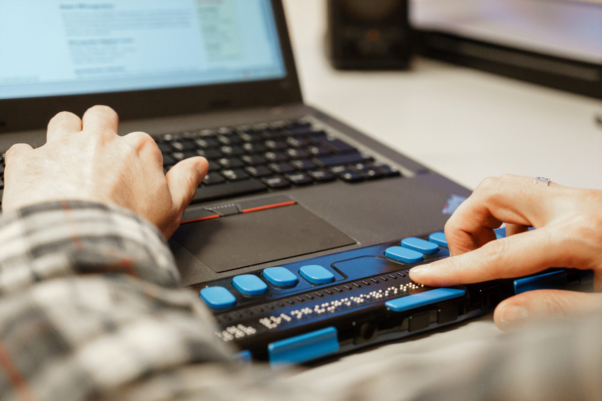 Web accessibility for people with visual impairments: The photo shows a close-up of hands on a refreshable braille display.
